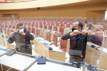 | Foto: Stefan Obermeier Zwei Männer halten durchsichtige Scheiben im Plenarsaal fest, sie bauen sie ab.