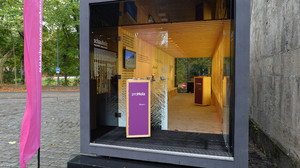 Eine Holzbox in Form eines Seefrachtcontainers dient als Ausstellungsraum. 